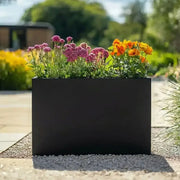 Black rectangular planter with pink and orange flowers in a garden setting